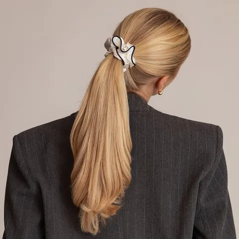 Sidenscrunchie i vit med mörkblå kant i tofs i tjockt blont hår som inte sliter på håret
