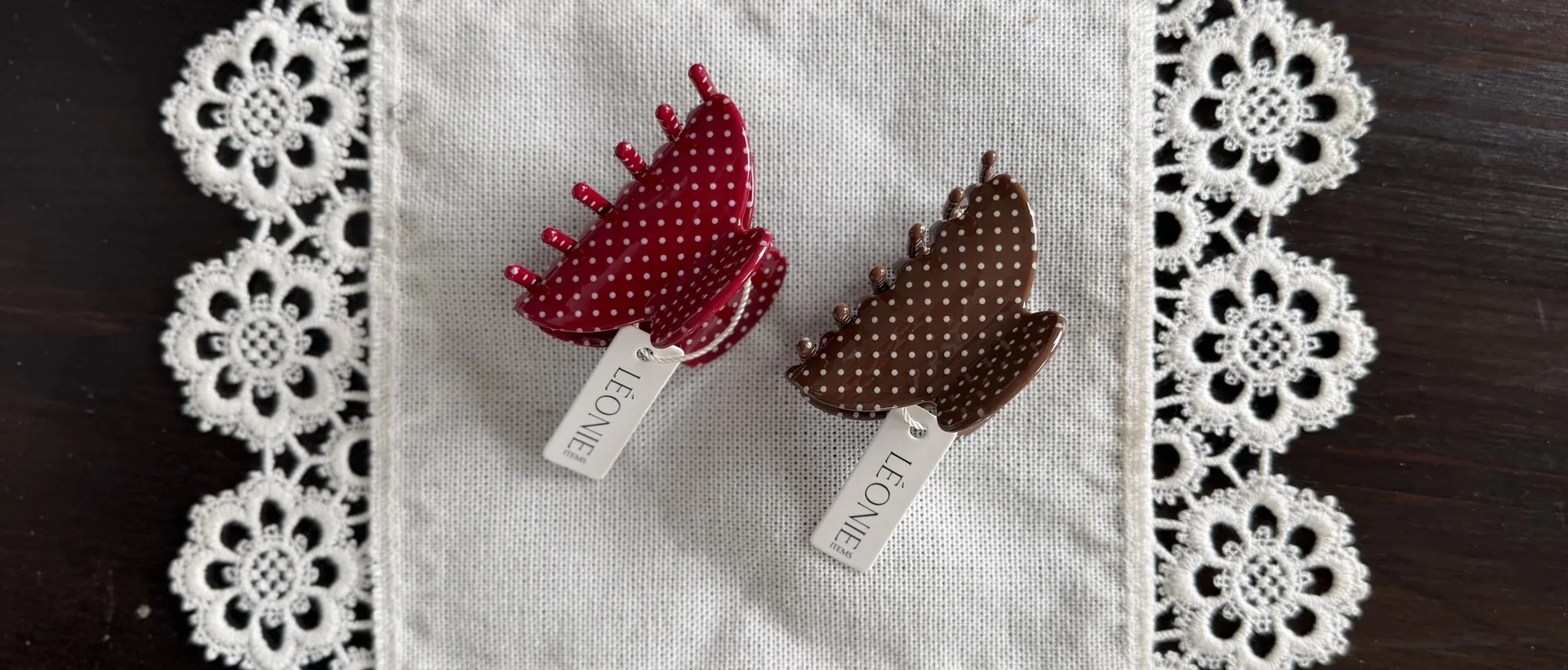 Nyhet: de prickiga hårklämmorna Ruby Dot och Mocca Dot ur Signature Collection på en spetsduk