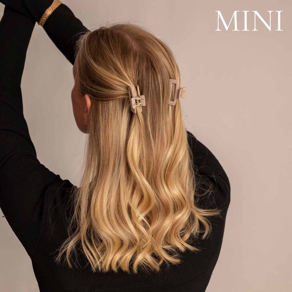 Två mini-hårklämmor i beige färg uppsatt i tvistad frisyr på blont hår